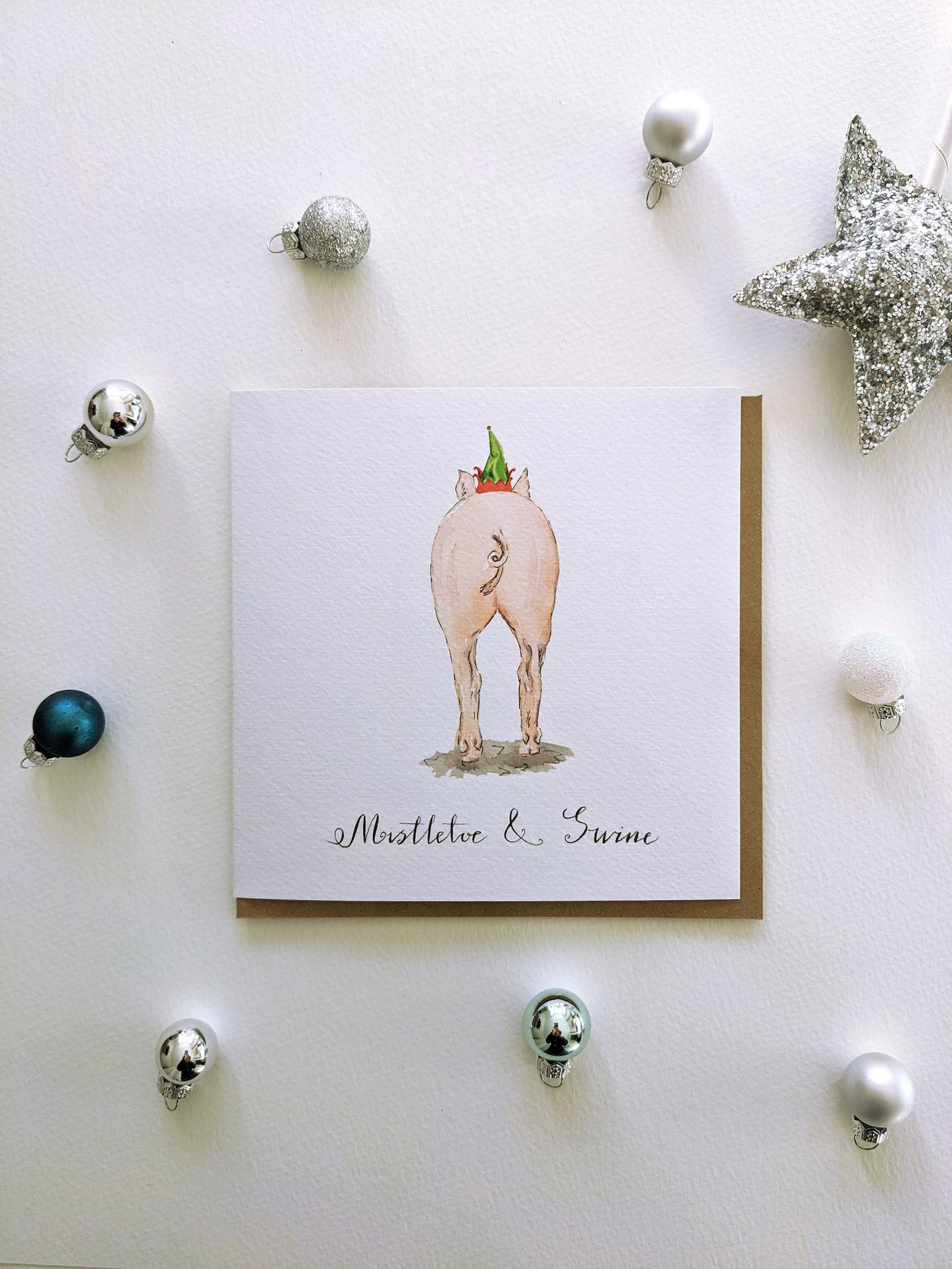 Mistletoe & Swine Christmas greeting card featuring a charming pig in an elf hat, a humorous and festive design by Jessica Kendrew.