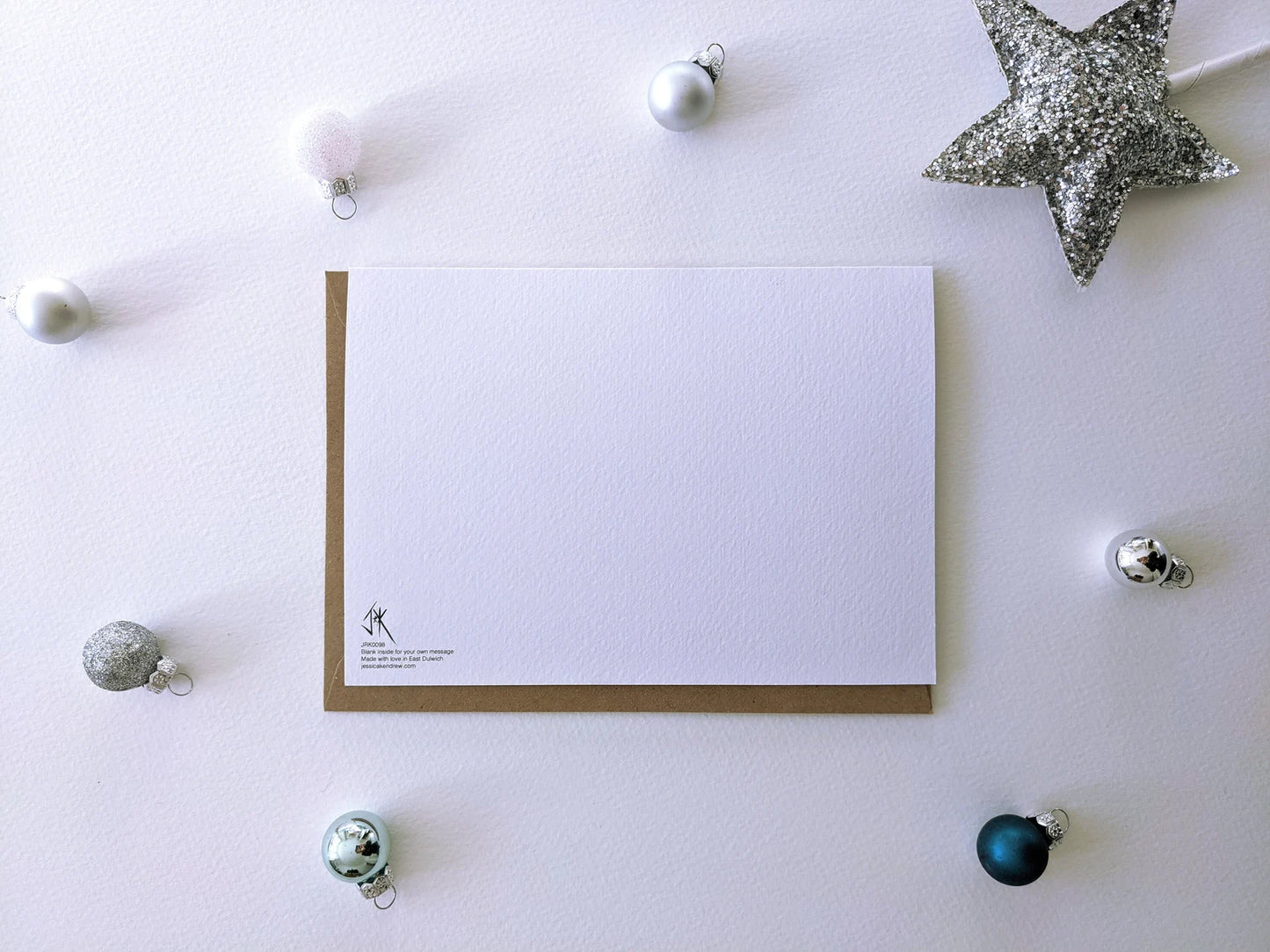 Back view of humorous Christmas card by Jessica Kendrew with brown kraft envelope on a sustainable background