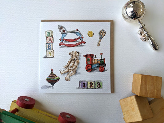 Jessica Kendrew watercolour vintage toy new baby greeting card featuring a teddy bear, rocking horse, toy train, blocks, rattle, ball, and spinning top on textured cardstock with a brown kraft envelope.