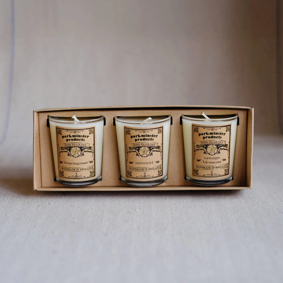 Gift set of three Parkminster summer-scented candles—Lemongrass, Coconut, and Orange Blossom—in clear glass votives, presented in a recycled kraft box with cream eco sleeve.