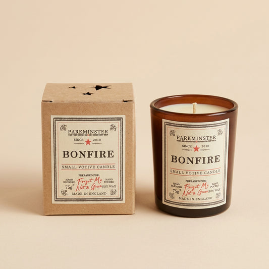 A Bonfire candle by Parminster shown with its amber glass jar and matching beige cardboard box, photographed on a neutral surface.