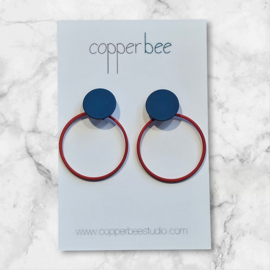 Copper bee earrings with blue and red design on a light blue card