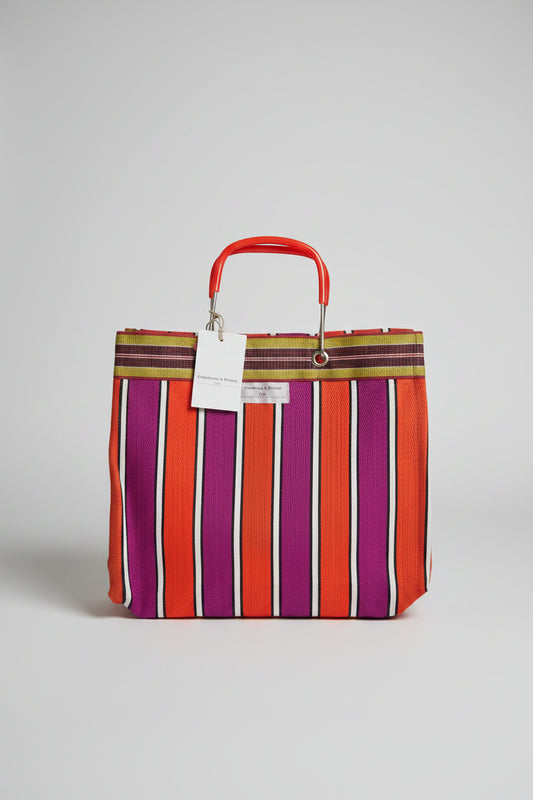 A striped tote bag with alternating orange, purple, and white vertical stripes with a metal handle