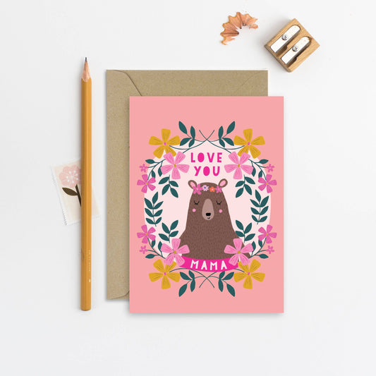 Mama Bear Greeting Card. Let your mum know how much she means to you with this illustrated card. With a peach background, intricate flower illustrations and a sweet mama bear, it's the perfect card to show her you love her.