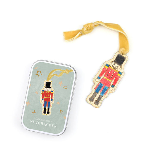 Child decorating a wooden vintage nutcracker ornament with watercolour pencils and eco glitter, inside a keepsake tin.